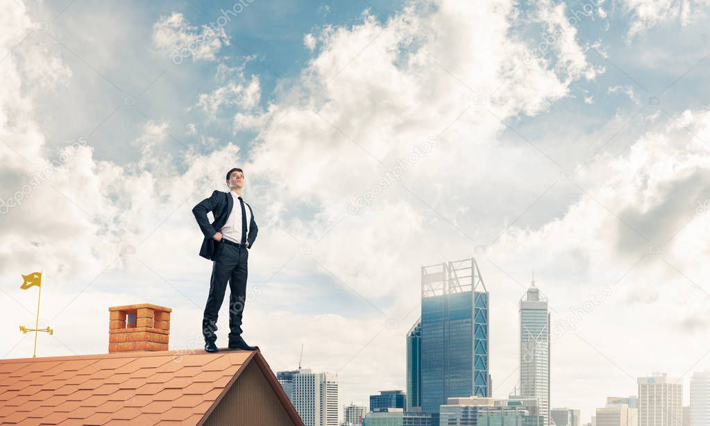 businessman standing on house roof 