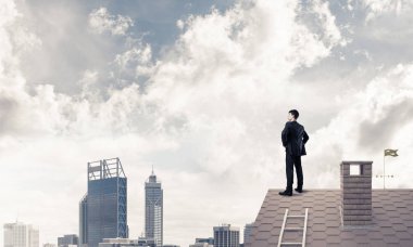 evin çatısında duran işadamı 