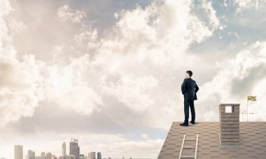 evin çatısında duran işadamı 