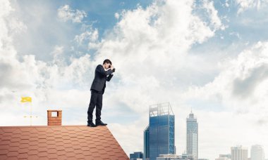 evin çatısında duran işadamı 