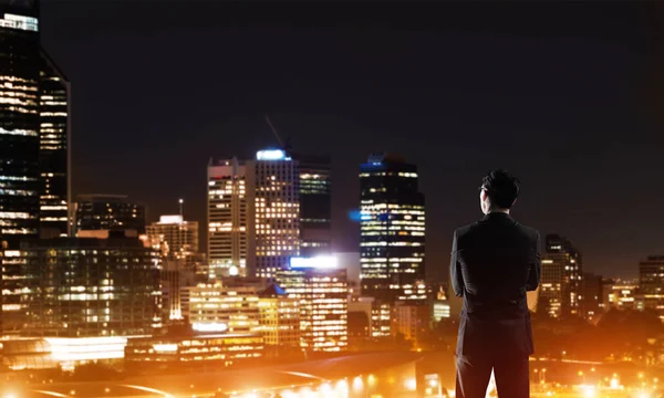 Podnikatel, zobrazení noci zářící město — Stock fotografie