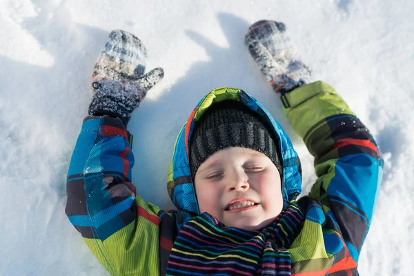 Roztomilý chlapec leží na sněhu — Stock fotografie