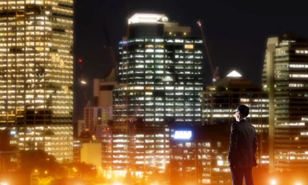 Businessman viewing night glowing city — Stock Photo, Image