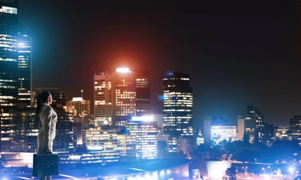 Zakenvrouw bekijken van lichten van de stad van de nacht — Stockfoto
