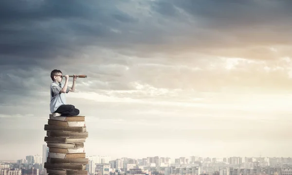 Kind sitzt auf Bücherstapel — Stockfoto