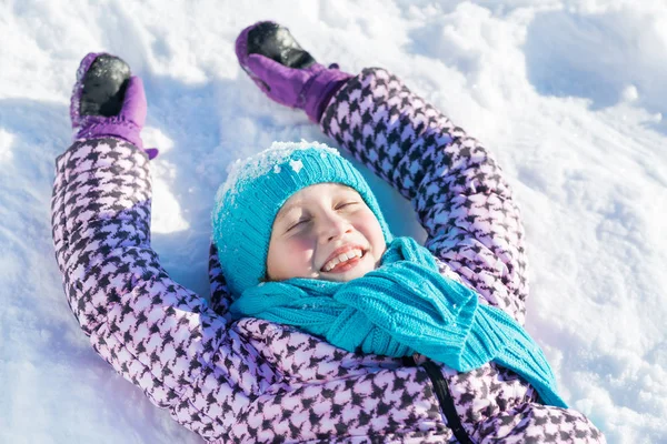 Menina deitada na neve — Fotografia de Stock