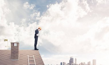 evin çatı kenarında duran işadamı 