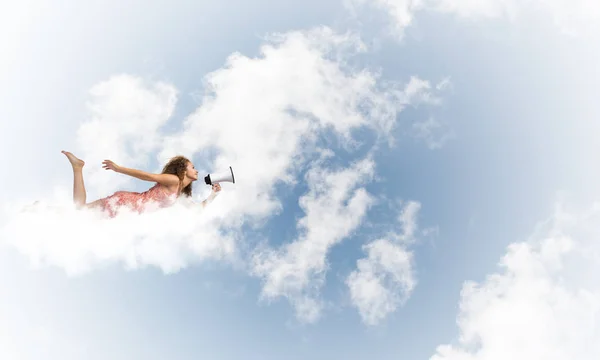 Mujer con megáfono volando alto en el cielo — Foto de Stock