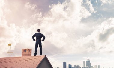 evin çatısında duran işadamı 