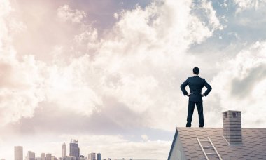 evin çatısında duran işadamı 