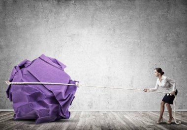 Genç bir kadın kocaman kağıt top hareketi yapıyor. 