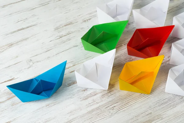 Conceito de liderança empresarial com barcos de papel branco e colorido em mesa de madeira — Fotografia de Stock