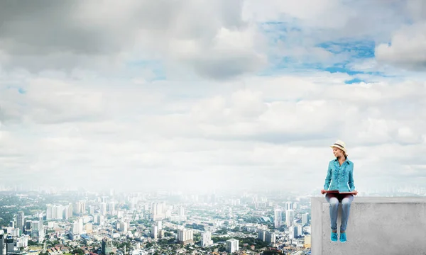 Woman sitting on top of building — Stock Photo, Image