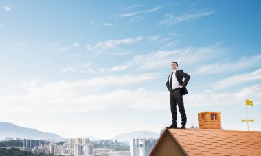 evin çatısında duran işadamı 