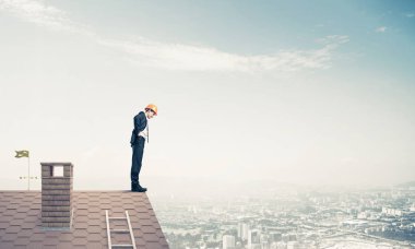 evin çatı kenarında duran işadamı 