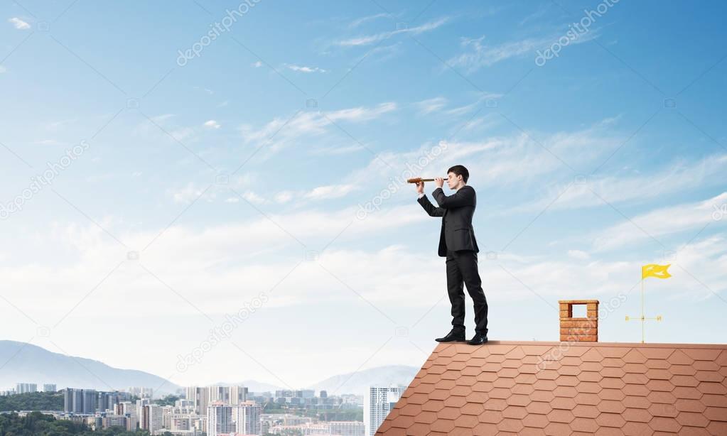 businessman standing on house roof 