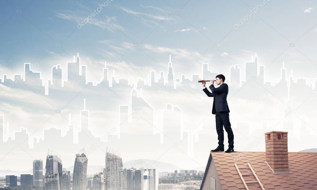 Young businessman in suit on roof edge
