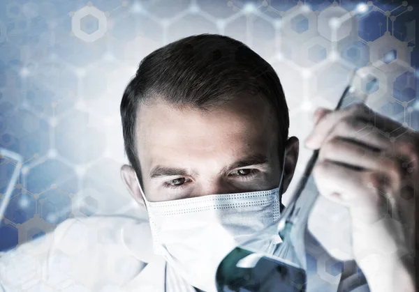 Νεαρός επιστήμονας που αναμιγνύει αντιδραστήρια σε γυάλινη φιάλη σε κλινικό εργαστήριο — Φωτογραφία Αρχείου