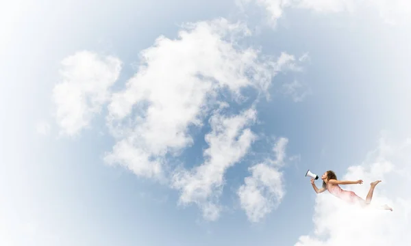 Woman with megaphone flying high in sky — Stock Photo, Image
