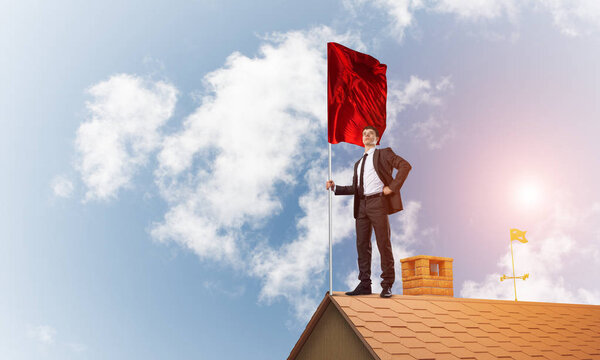 Businessman standing on house roof 