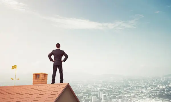 Hombre de negocios de pie en el techo de casa — Foto de Stock