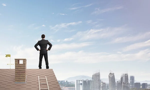Biznesmen, stojąc na dachu domu — Zdjęcie stockowe