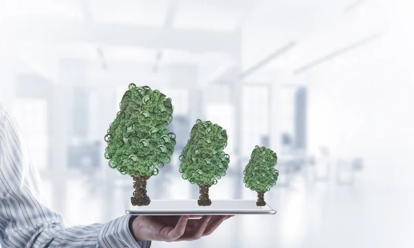Affärsman som håller TabletPC med gröna träd — Stockfoto