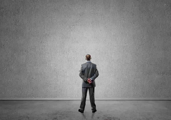 Businessman looking at blank concrete wall — Stock Photo, Image