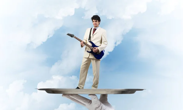 Бизнесмен на подносе играет на акустической гитаре — стоковое фото
