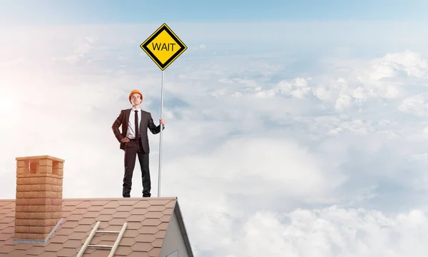 Young businessman on house brick roof