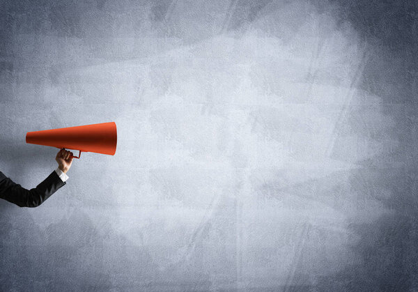 Hand of businesswoman holding red paper trumpet