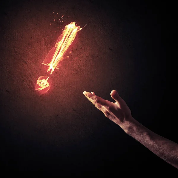 Mão com fogo brilhando ponto de exclamação — Fotografia de Stock