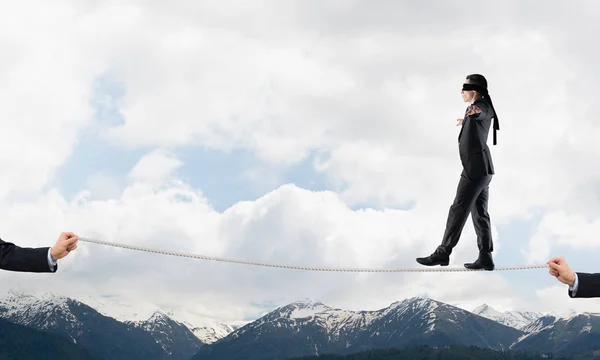 Businessman with blindfold on eyes walking on rope — Stock Photo, Image