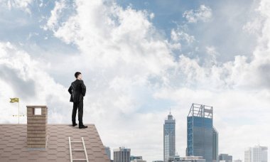 Evin çatısında duran genç işadamı 