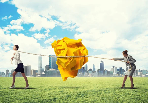 Mujeres de negocios tirando de gran bola arrugada — Foto de Stock