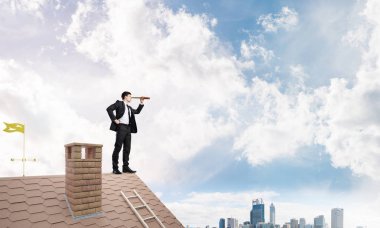 Evin çatısında duran genç işadamı 