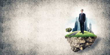 Yeşil yüzen ada üzerinde duran işadamı