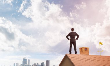 Evin çatısında duran genç işadamı 