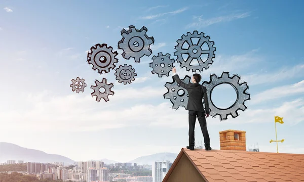 Young businessman standing on house roof