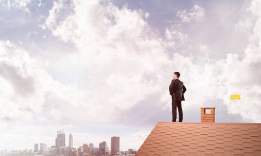 Evin çatısında duran genç işadamı 