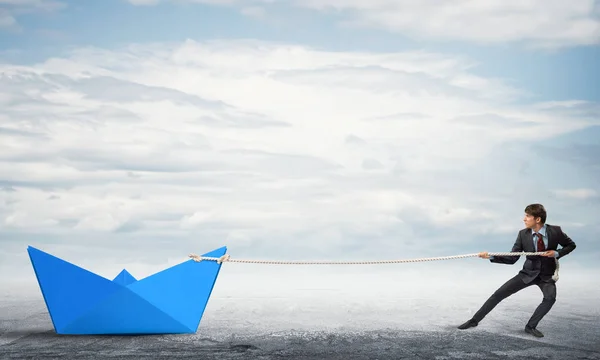 businessman pulling with rope paper boat