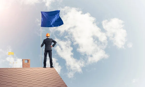 Businessman standing on house roof — Stock Photo, Image