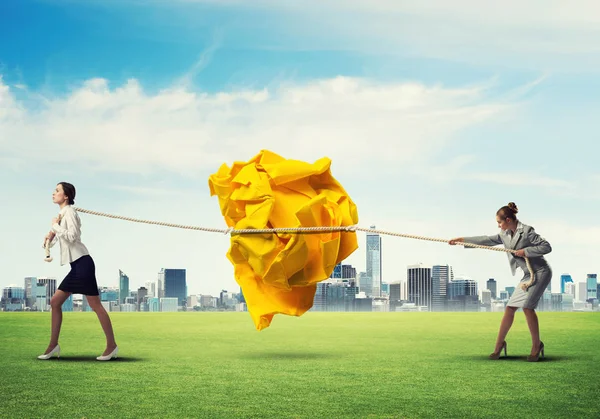 Mujeres de negocios tirando de gran bola arrugada — Foto de Stock