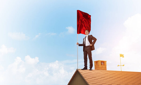 Businessman standing on house roof 