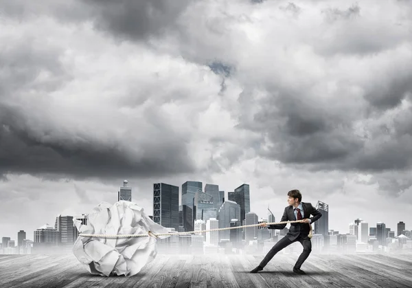 Businessman pulling with effort paper ball — Stock Photo, Image