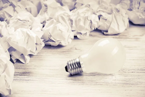 Balls of crumpled paper and light bulb Royalty Free Stock Images
