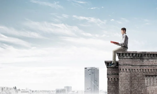 Hombre sentado en parapeto con libro rojo — Foto de Stock