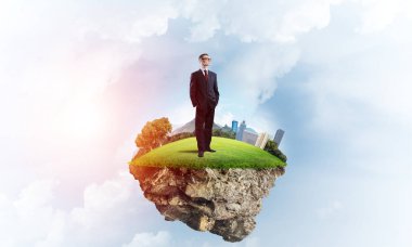 Yeşil yüzen ada üzerinde duran işadamı