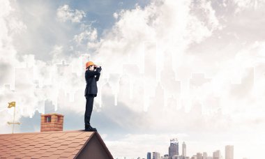 Takım elbise ve kask çatıda genç işadamı 