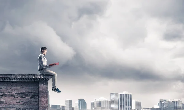 Homem sentado em parapeito com livro vermelho — Fotografia de Stock